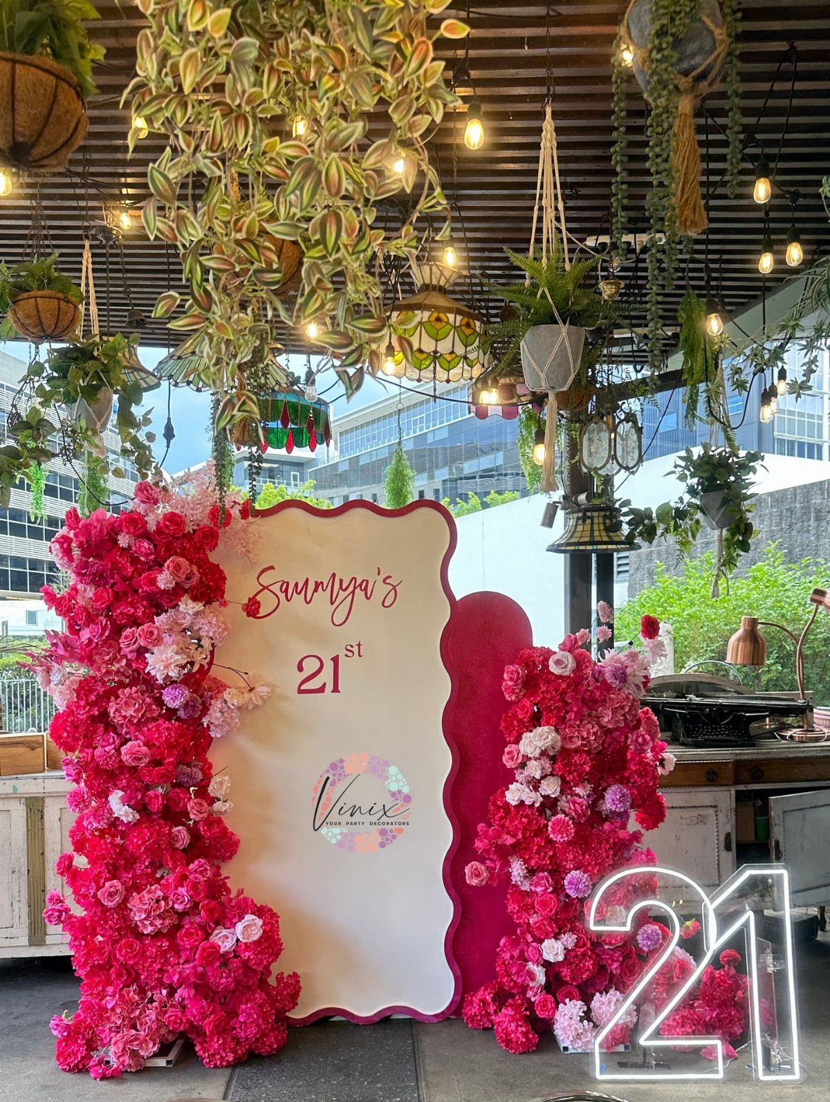 White scalloped birthday sign for a 21st birthday decorated with pink and red flowers.