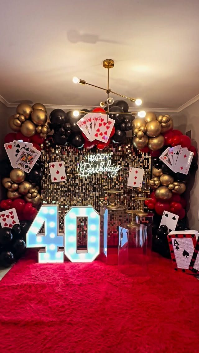 40th birthday party decorations with red carpet, gold balloons, and giant playing cards.