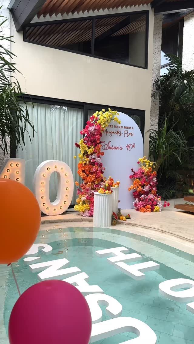 Floral birthday decorations with large glowing 40 numbers and a flower-covered backdrop.