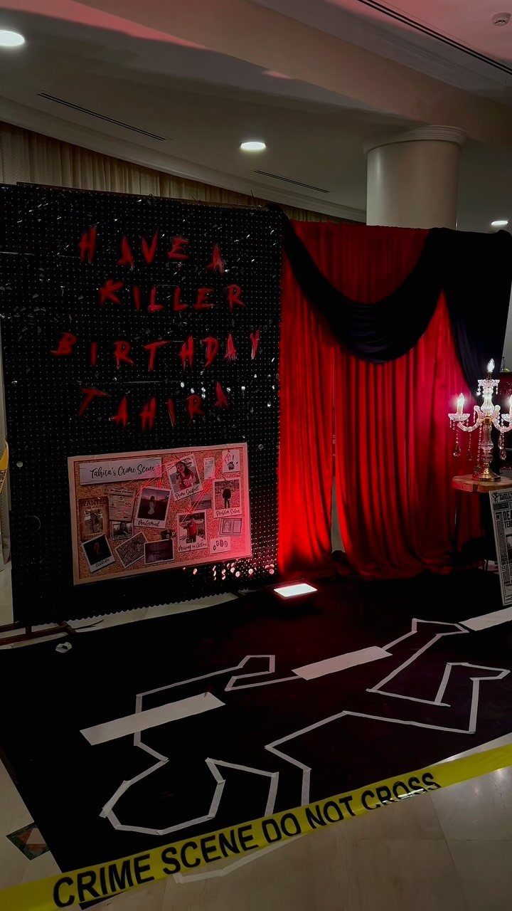 Crime scene themed birthday party setup with red curtains and police tape.