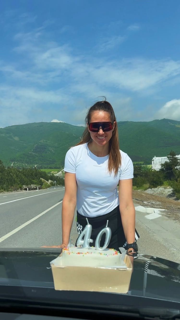 Woman celebrating 40th birthday with a cake on a car during a road trip.