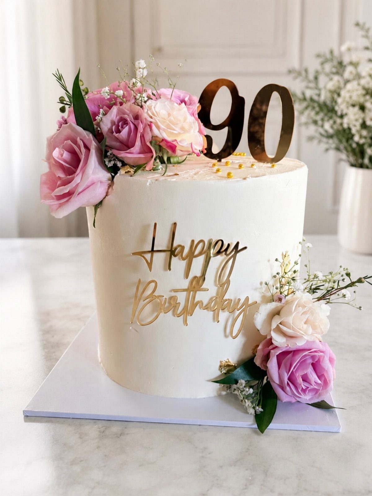 White birthday cake with pink roses and gold 90 Happy Birthday toppers