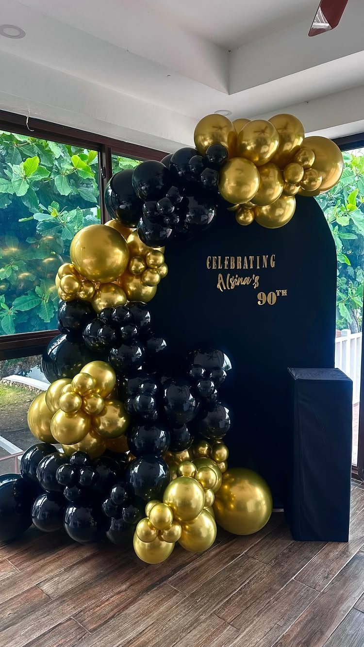 Black arched backdrop with gold and black balloon garland for 90th birthday celebration