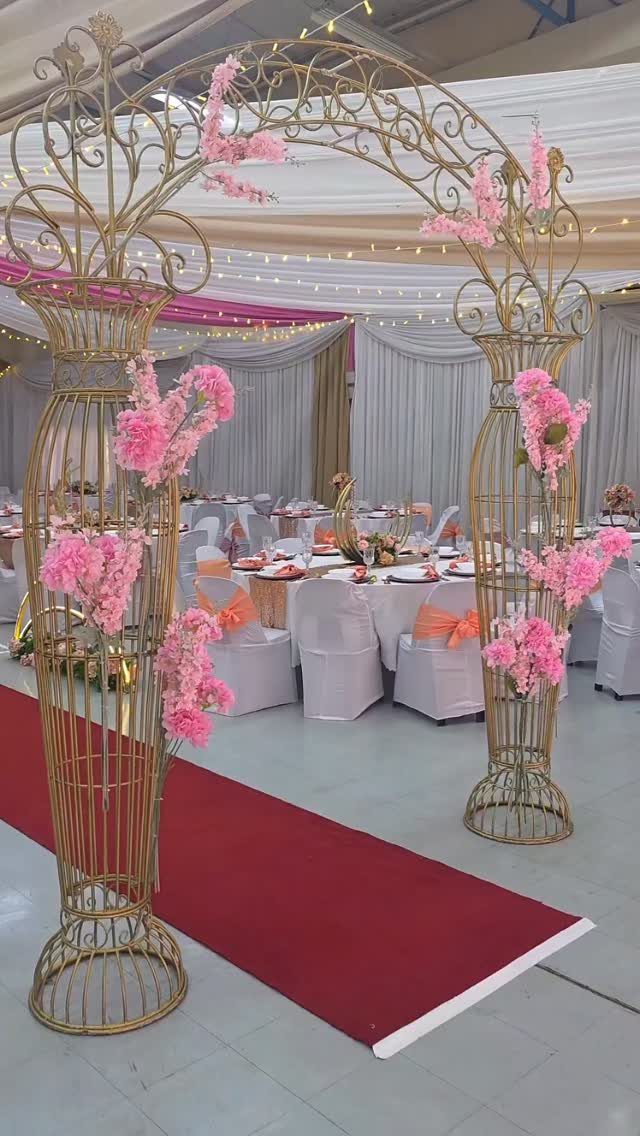 Gold ornate floral arch and red carpet leading into a decorated banquet hall