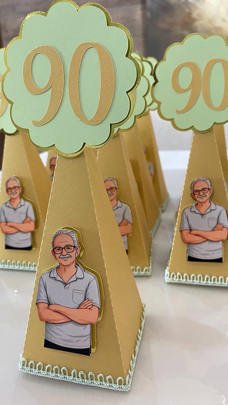 Gold pyramid party favors with cartoon man illustrations and 90 birthday toppers.
