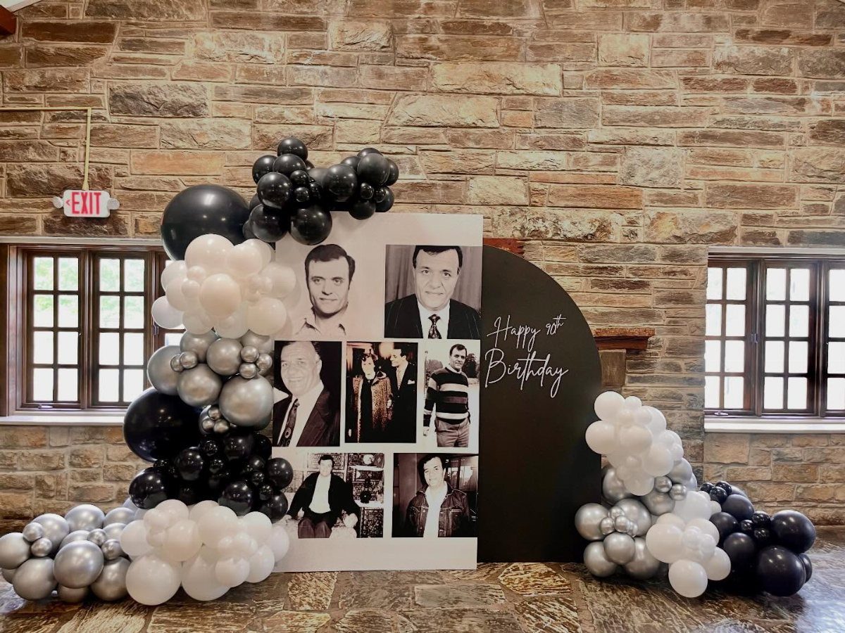 Birthday backdrop with black and white portraits, balloons, and Happy 90th Birthday sign.