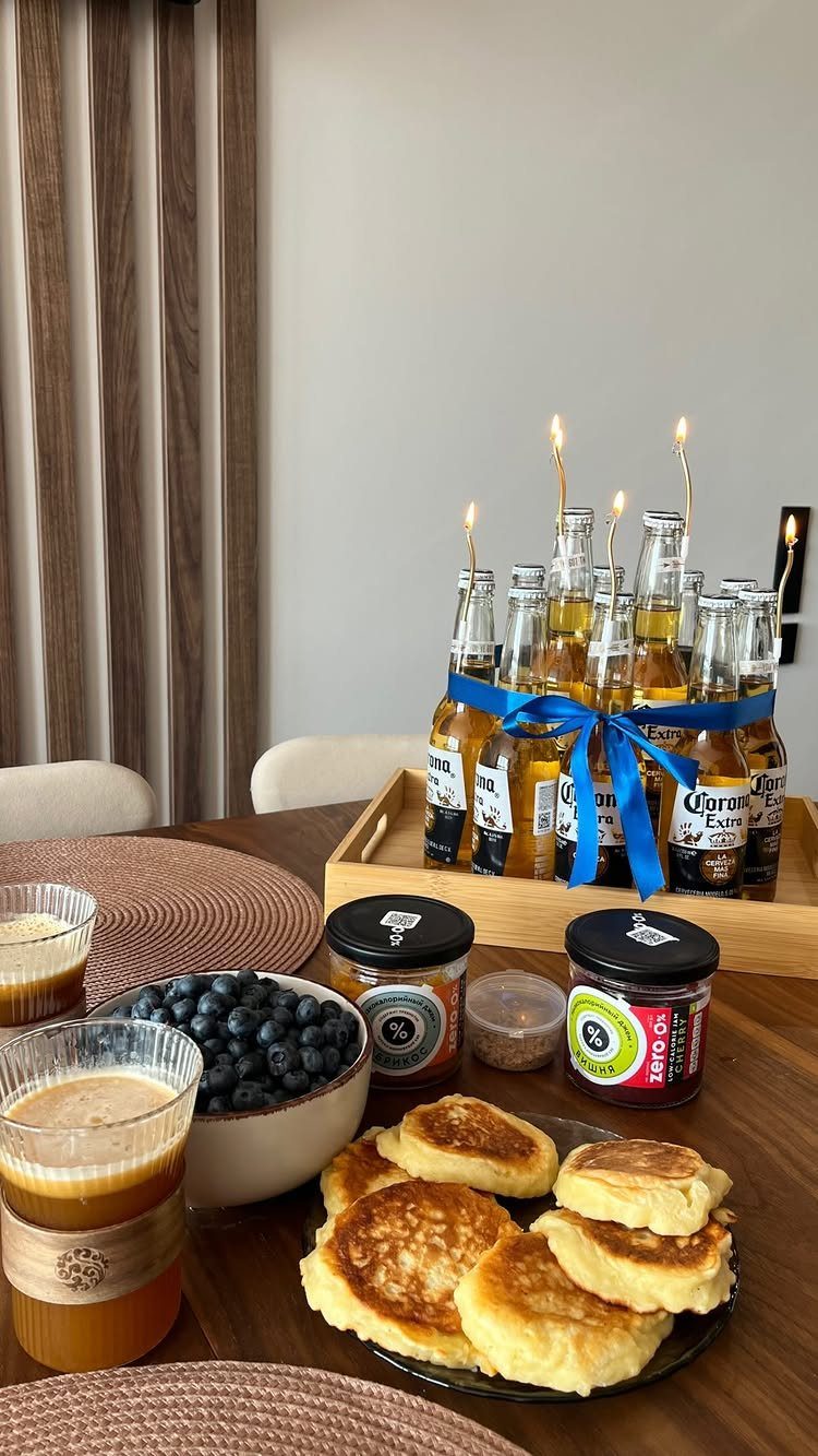 Breakfast pancakes and blueberries with Corona beer bottles and lit sparklers on a table