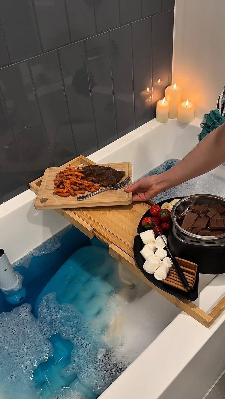 Wooden bathtub tray with steak, fries, and chocolate fondue over blue bubbly water
