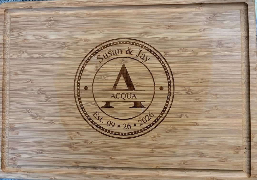Bamboo cutting board with a circular engraved personalized design featuring names and date.