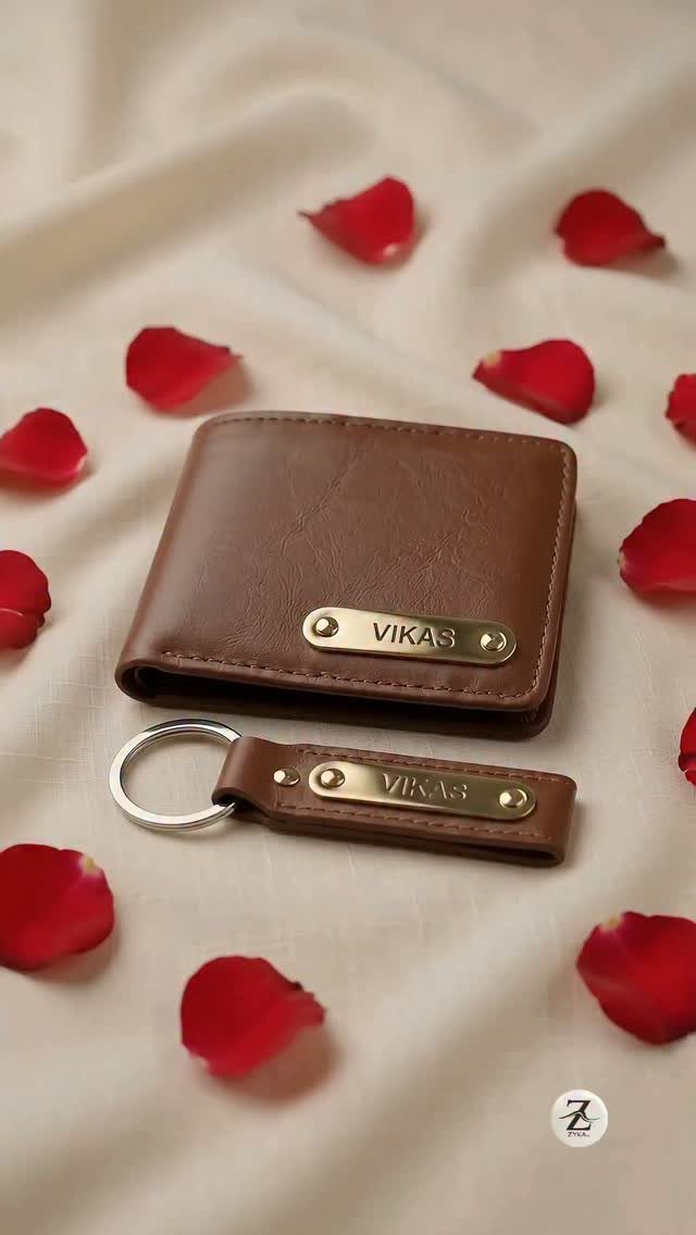 Brown leather wallet and keychain with engraved name plates among red rose petals