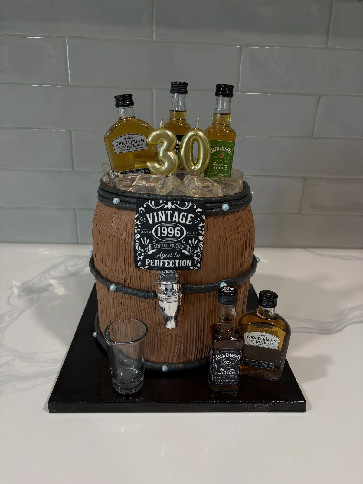 Wooden whiskey barrel cooler with ice, miniature liquor bottles, and a 30th birthday candle.