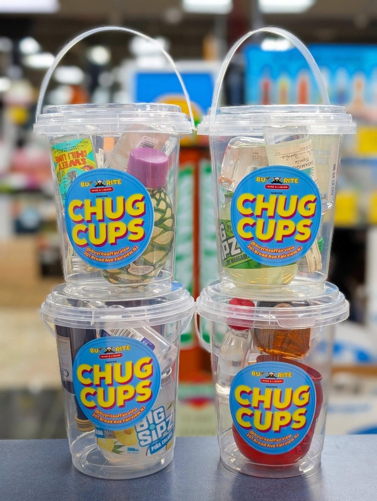 Four clear plastic buckets filled with mini drink bottles and snacks labeled Chug Cups.