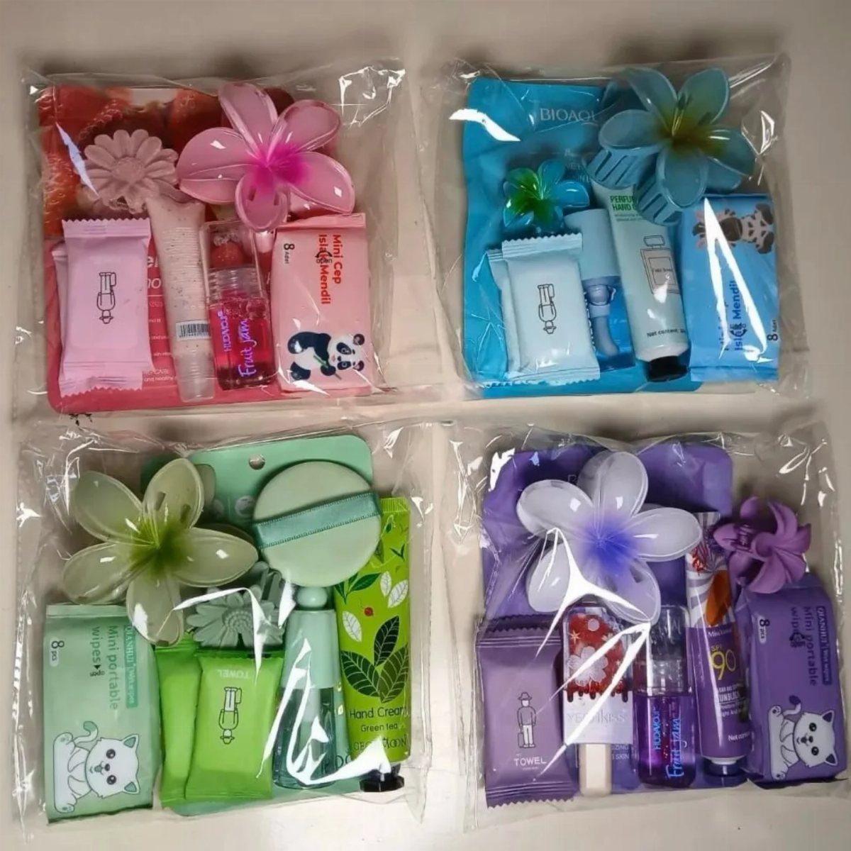 Four colorful travel-sized skincare sets in clear bags decorated with plastic flowers.