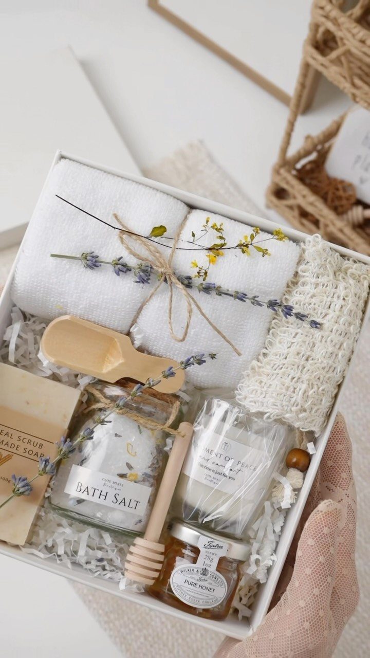 Self-care gift box with white towels, bath salts, honey, and a scented candle.