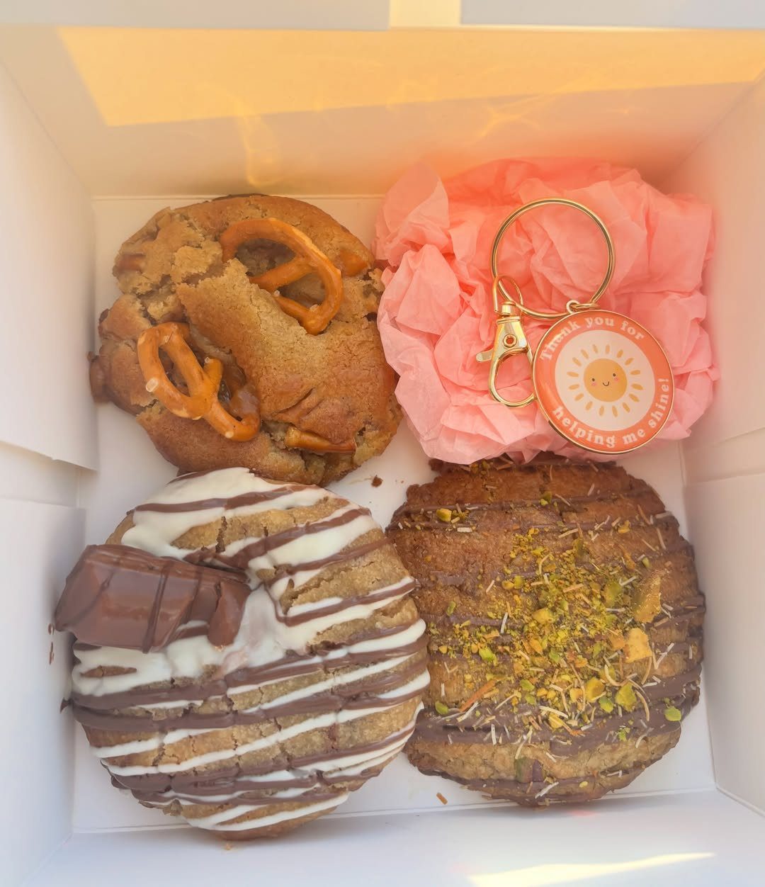 Gourmet cookies and a sun keychain in a white gift box with pink tissue.