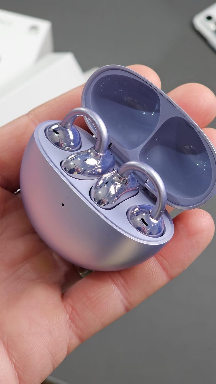 Purple wireless earbuds in an open charging case held by a hand.