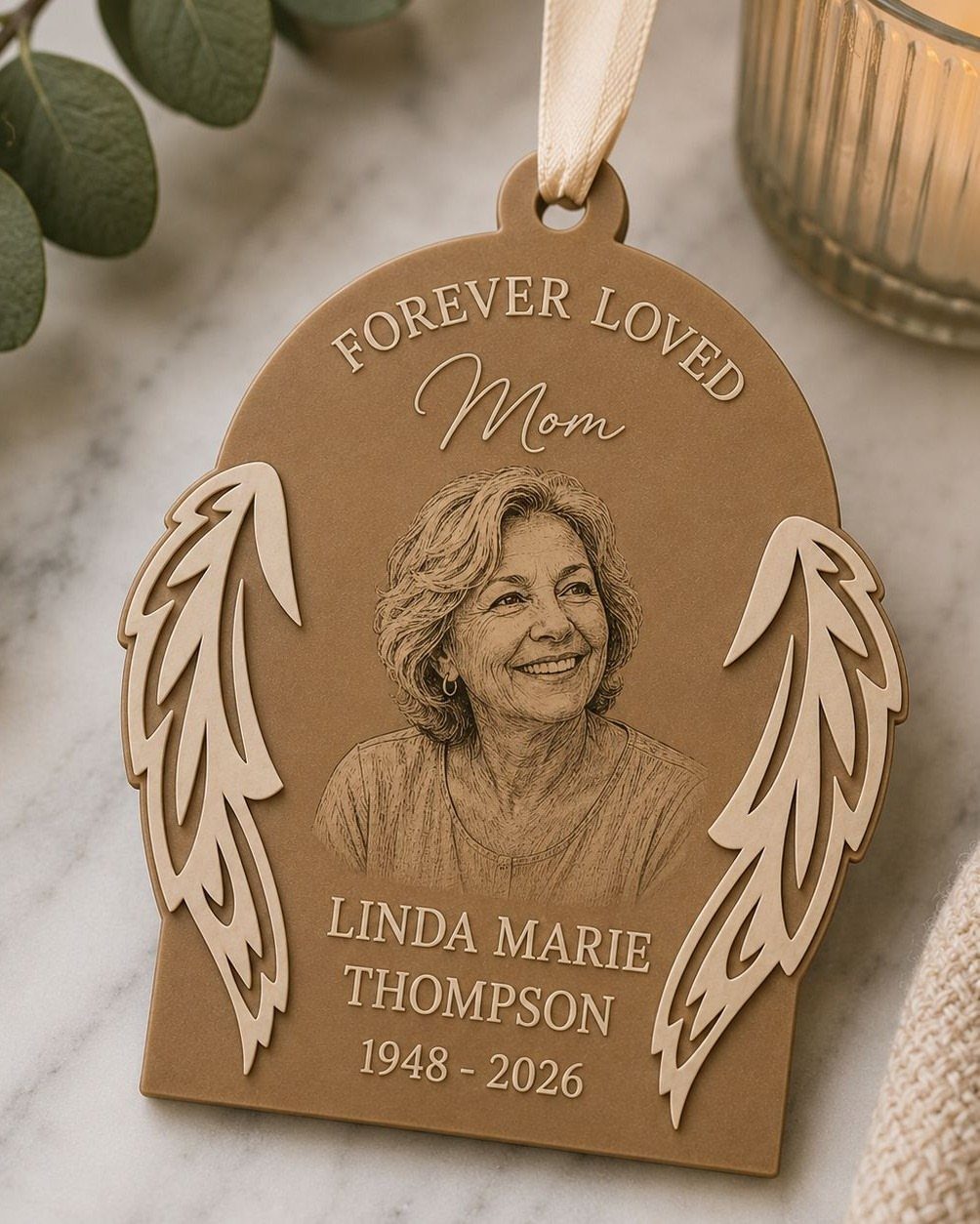 Wooden memorial ornament with engraved portrait of a woman and angel wings.