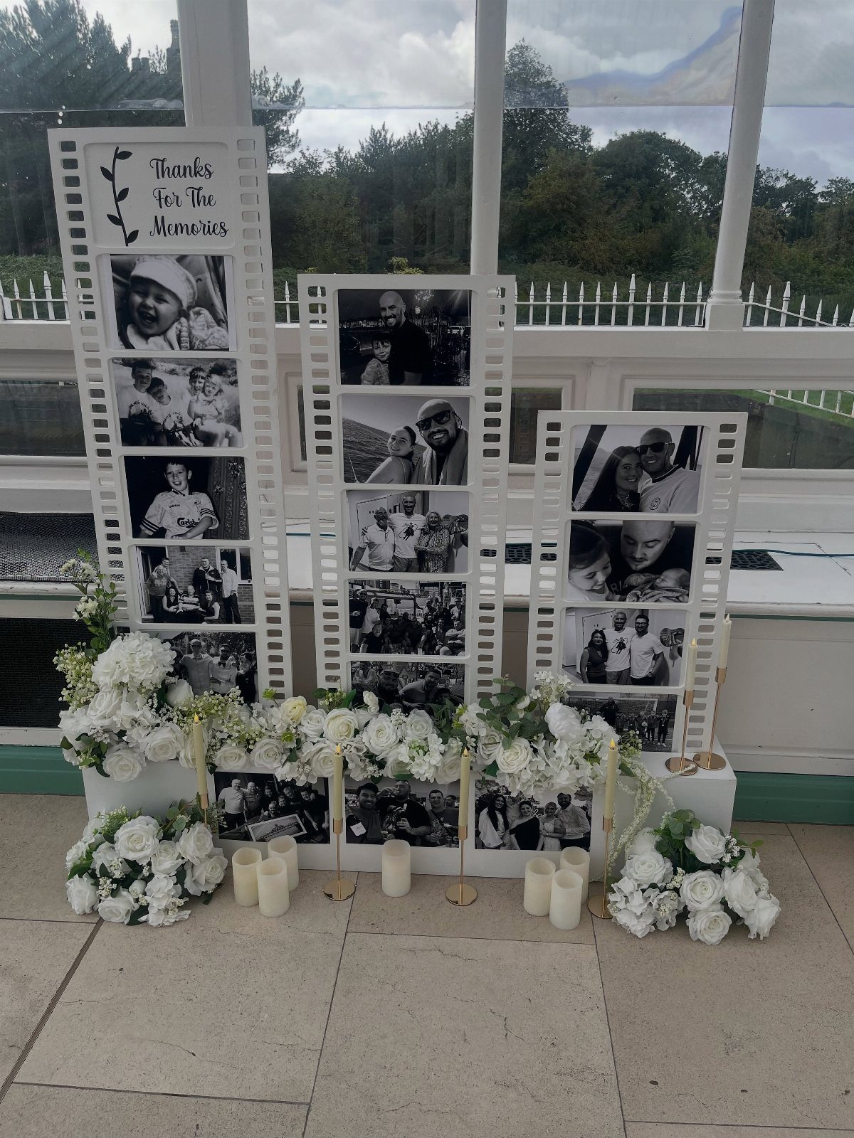 Film strip memory boards with black and white photos, white flowers, and candles.