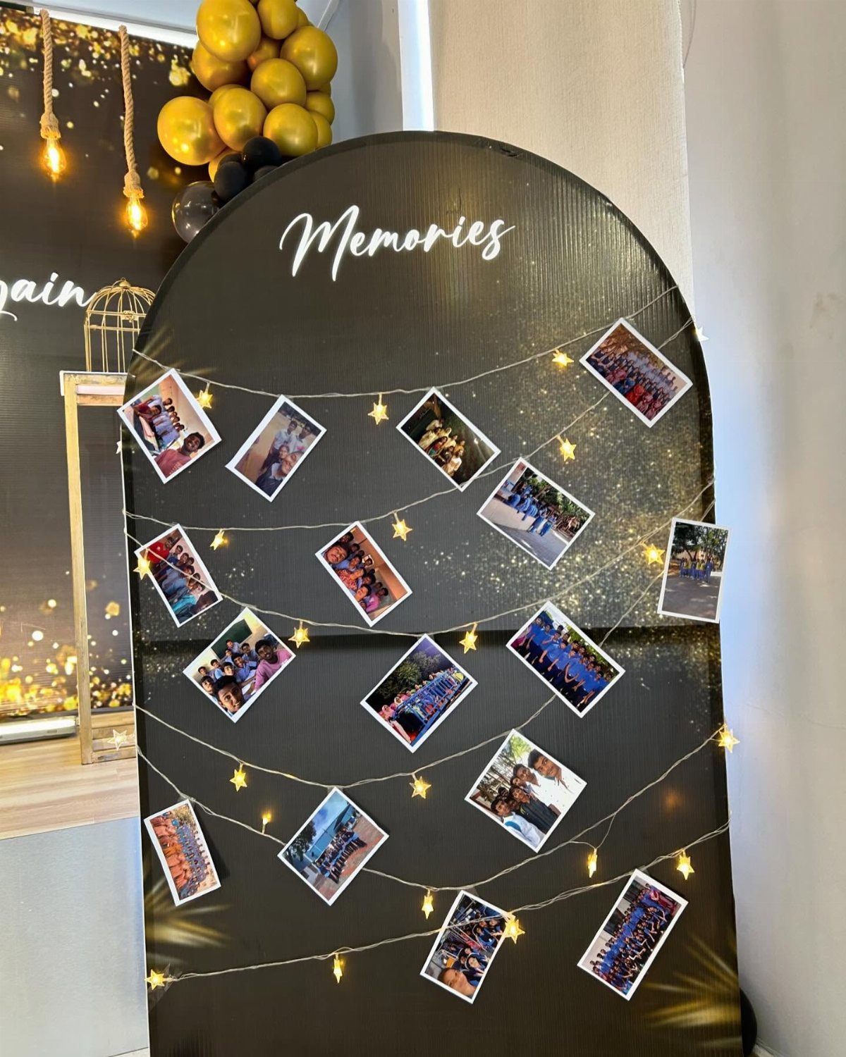 Black arched memory board with photographs clipped to twinkling fairy lights and white script.