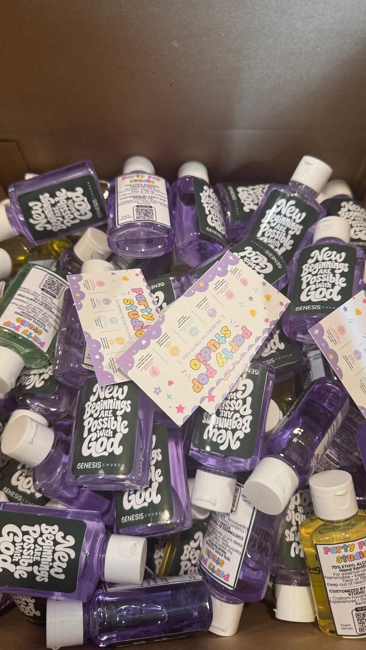 Small bottles of purple and yellow hand sanitizer with custom labels in a box.