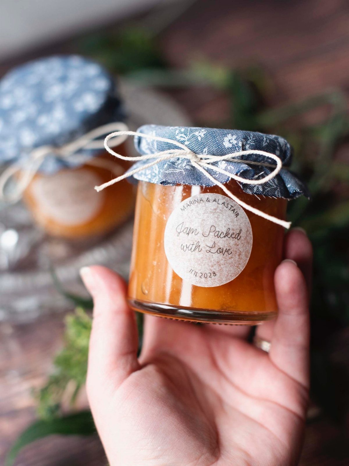 Small glass jar of orange jam with floral fabric lid and twine tie.