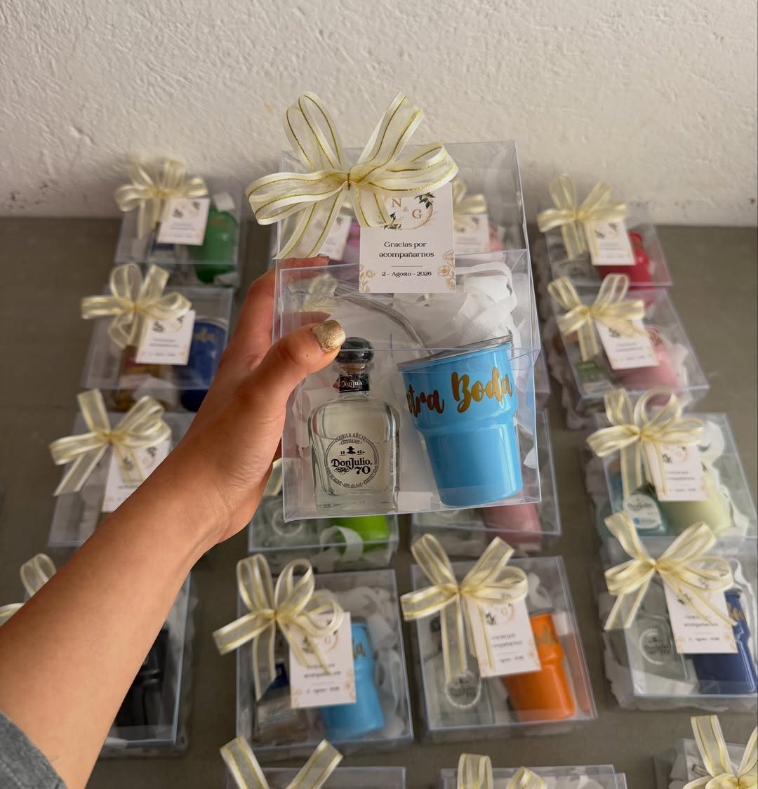 Mini cocktail kits in clear gift boxes with bows, featuring liquor and tumblers.