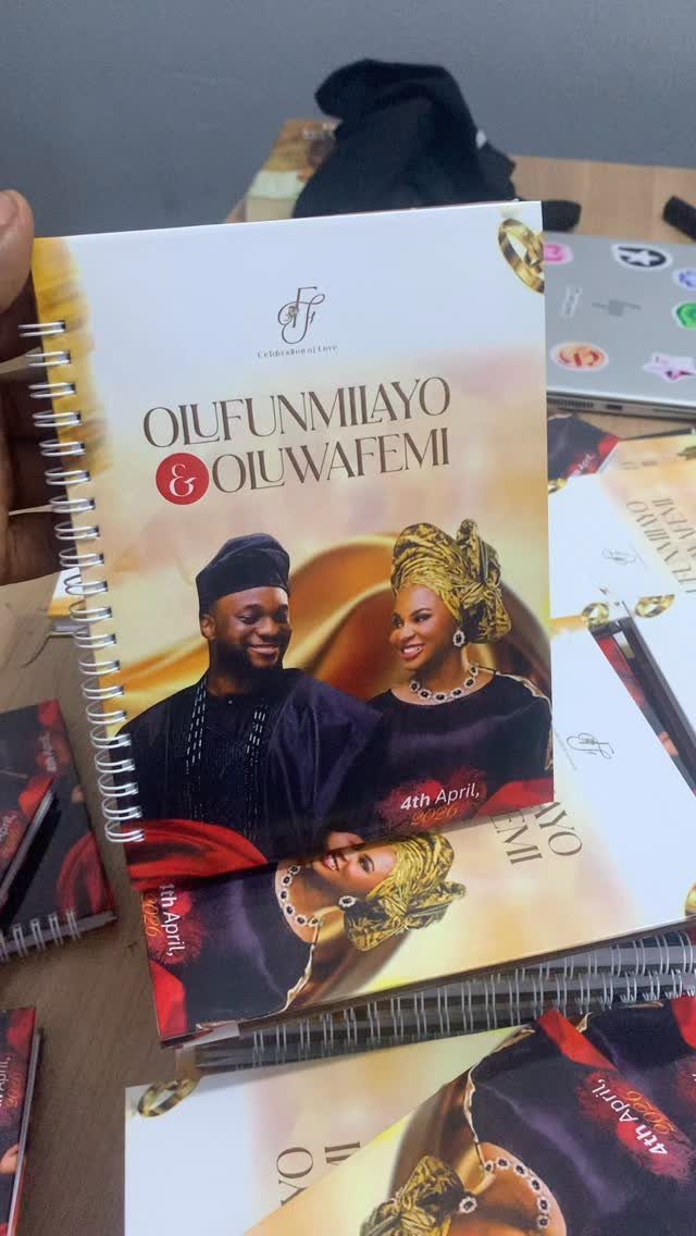 Spiral-bound notebooks with a custom wedding photo cover on a wooden table.