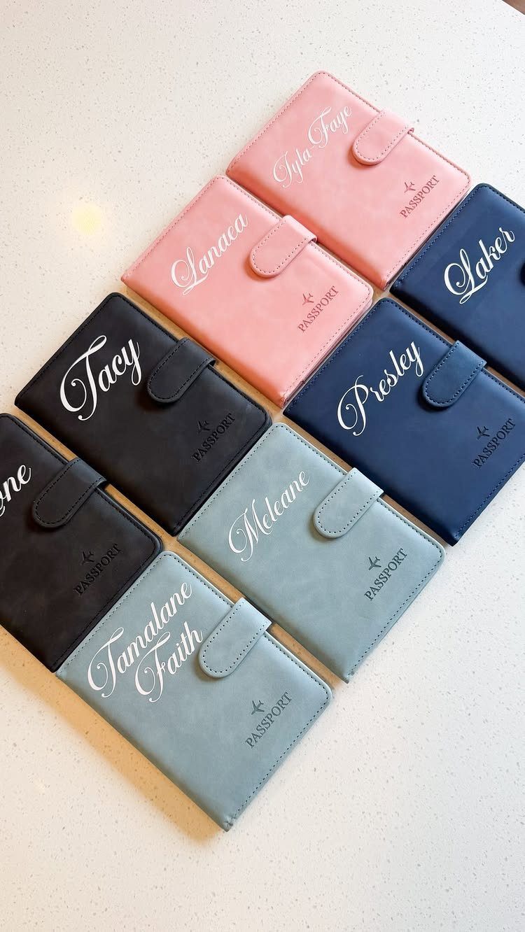 Personalized faux-leather passport covers in various colors with names written in white cursive.