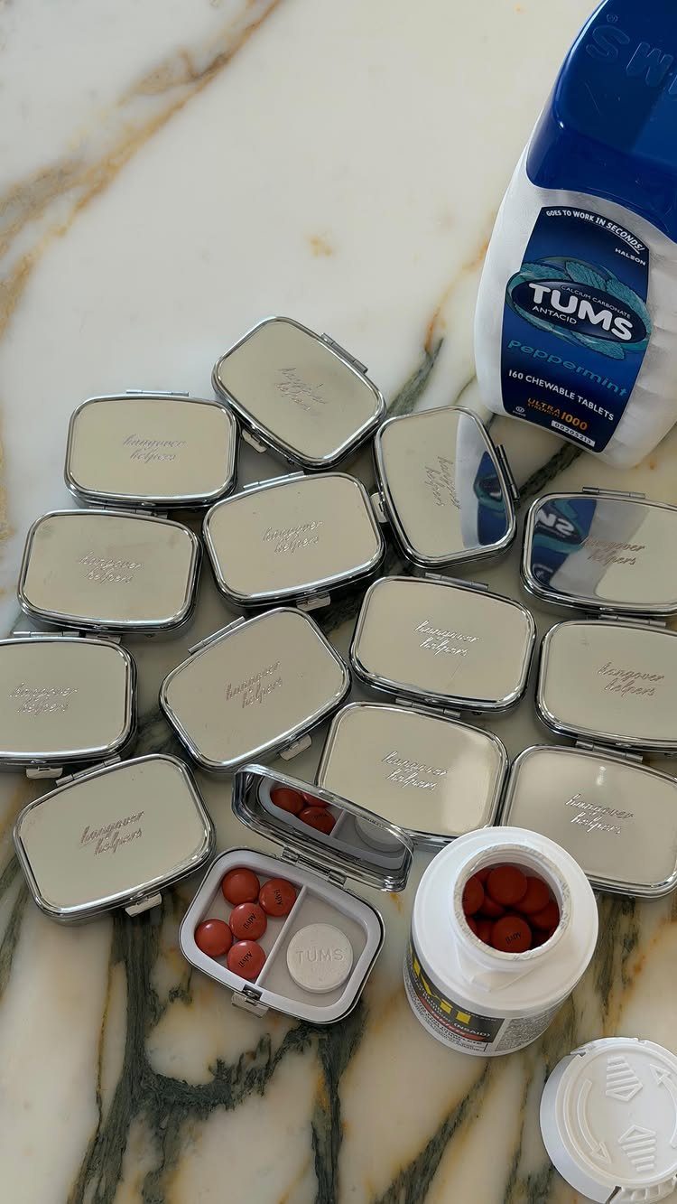 Small silver tins filled with red antacid tablets on a white marble surface.