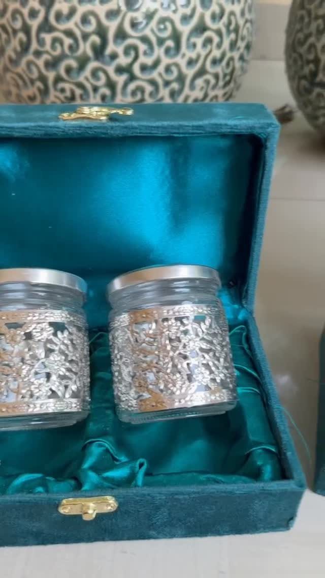Two small glass jars with silver filigree wraps in a teal velvet box.