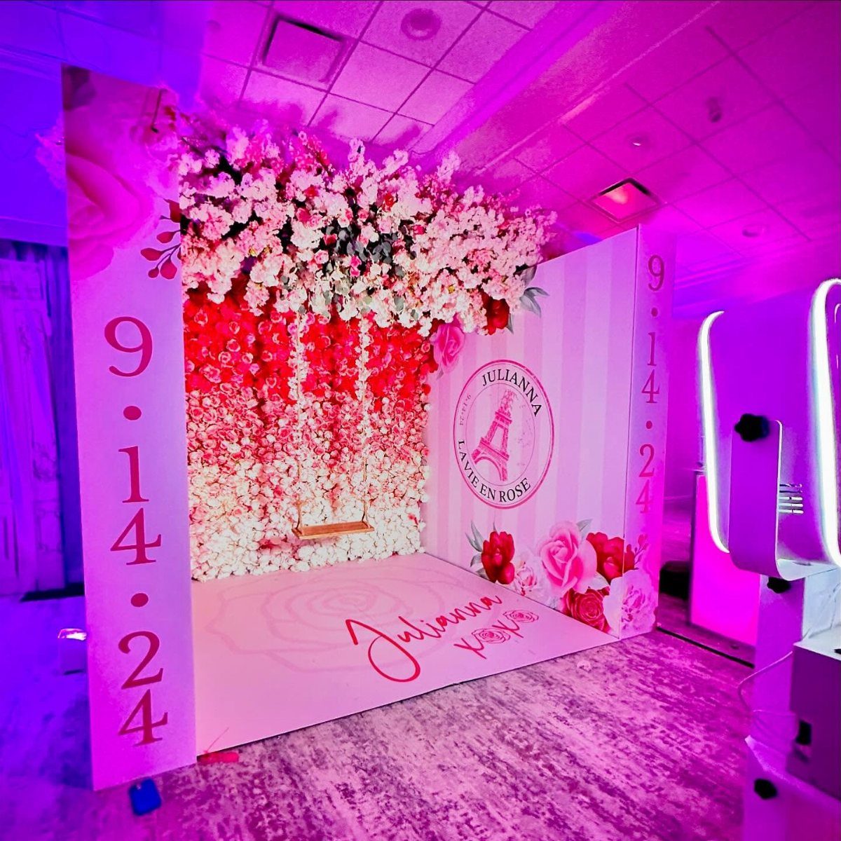 Pink floral photo booth backdrop with a swing and personalized floor lettering.