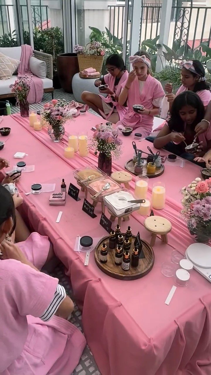 Teenage girls in pink robes enjoying a spa day at a decorated table.