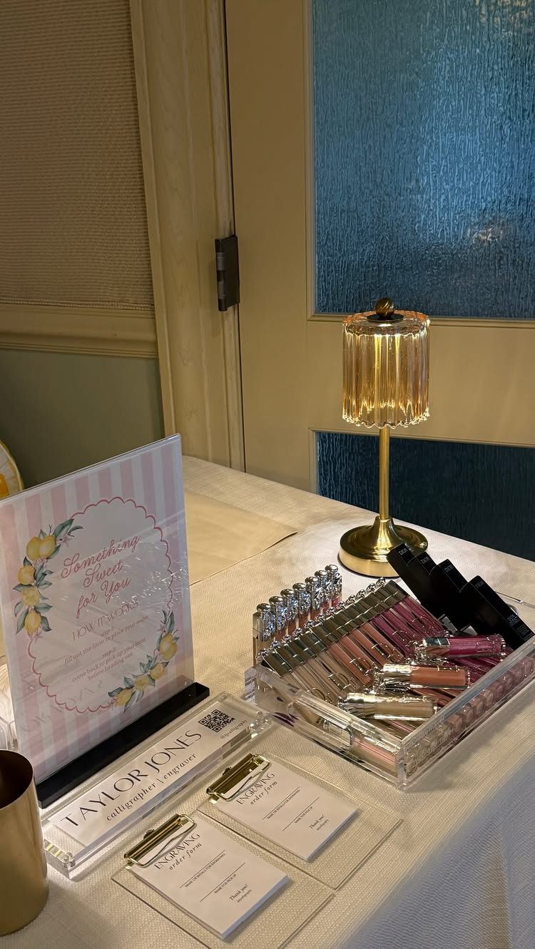 Lip gloss party favors in a clear organizer next to a floral sign.