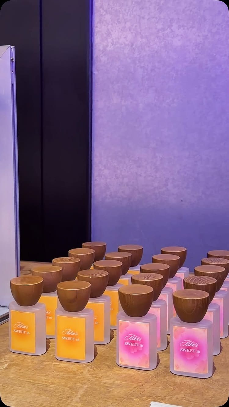 Small square perfume bottles with wooden caps and pink and yellow liquids.