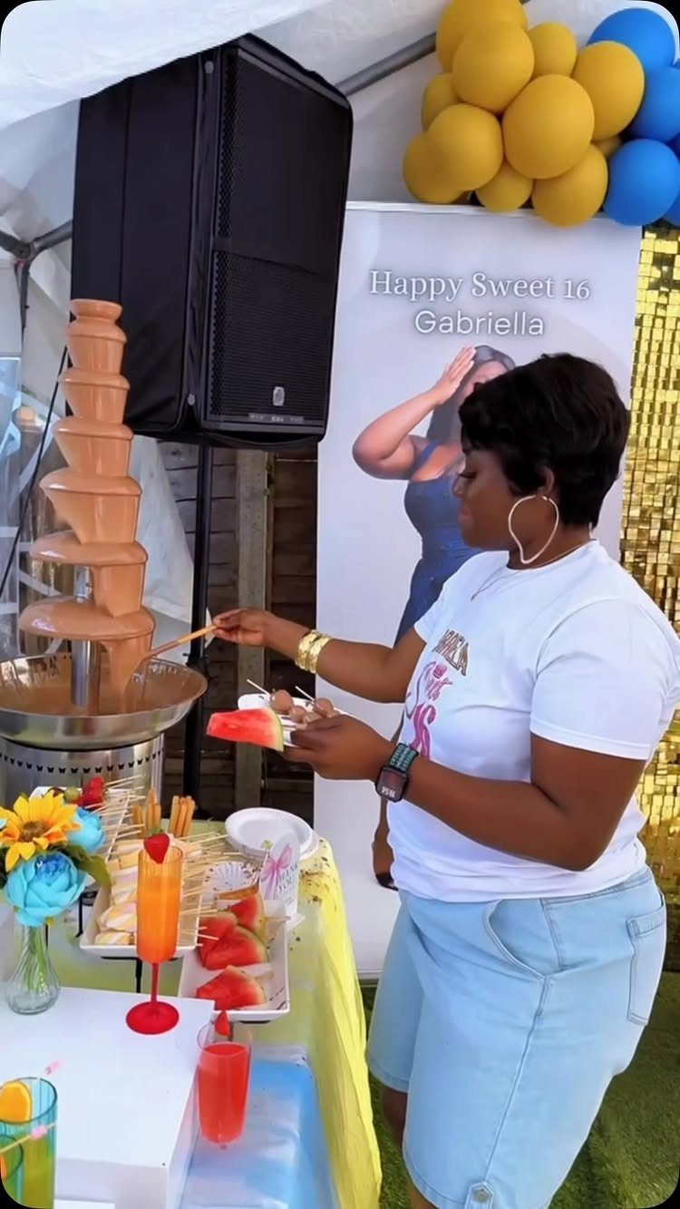 Woman dipping food into a chocolate fountain at a Sweet 16 party.