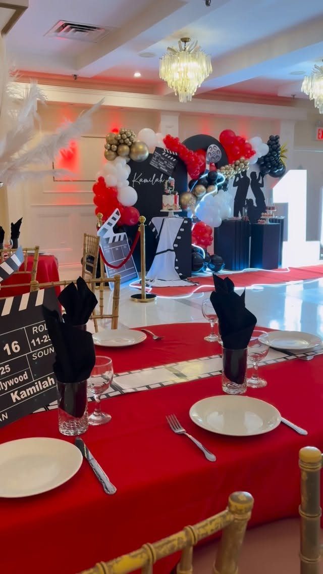 Red and black party table settings with a Hollywood themed balloon backdrop.