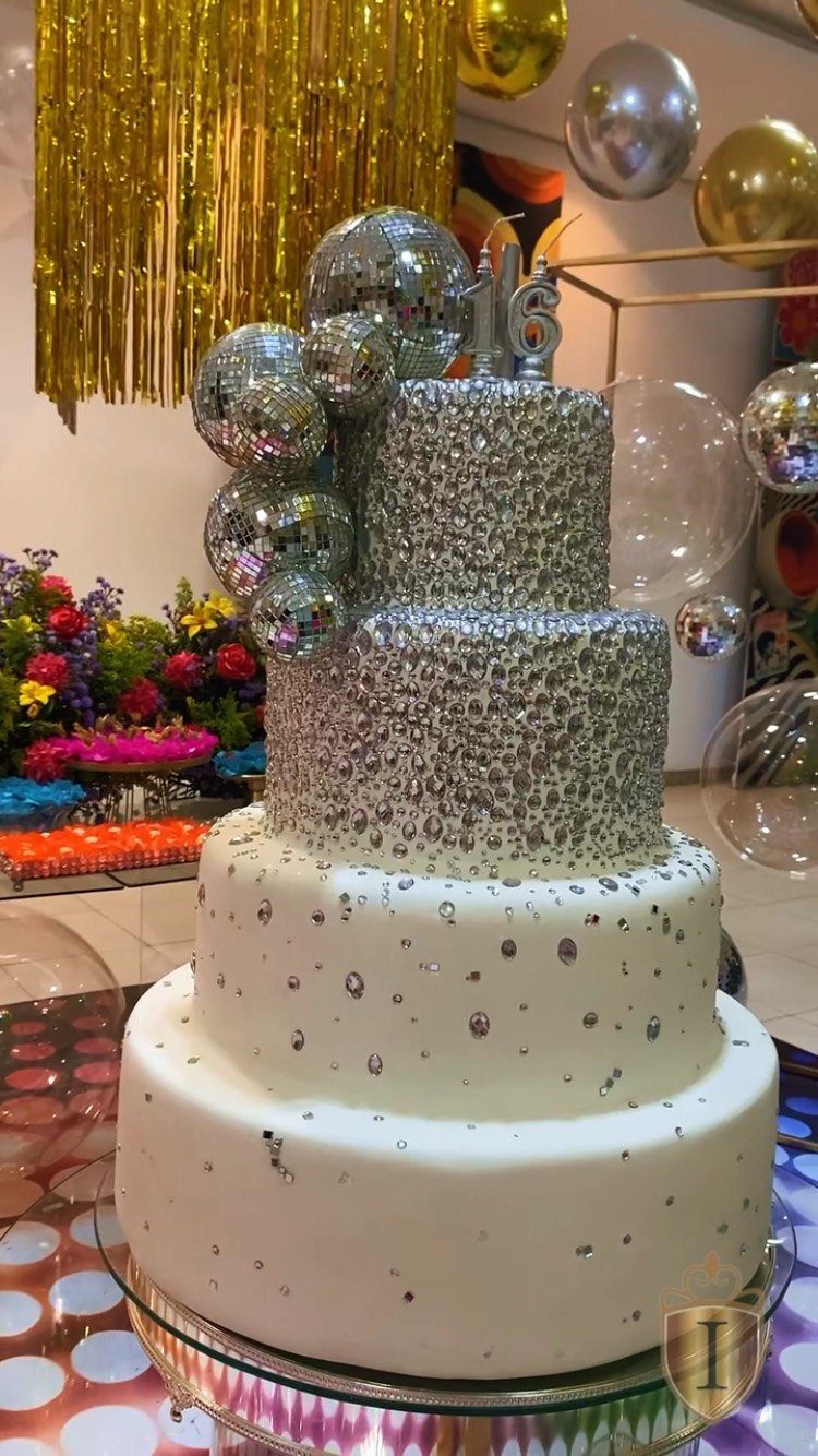 Four-tier silver and white cake with disco balls and a 16 topper.