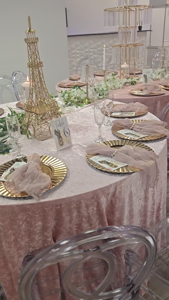 Pink velvet table setting with a gold Eiffel Tower centerpiece and gold plates.