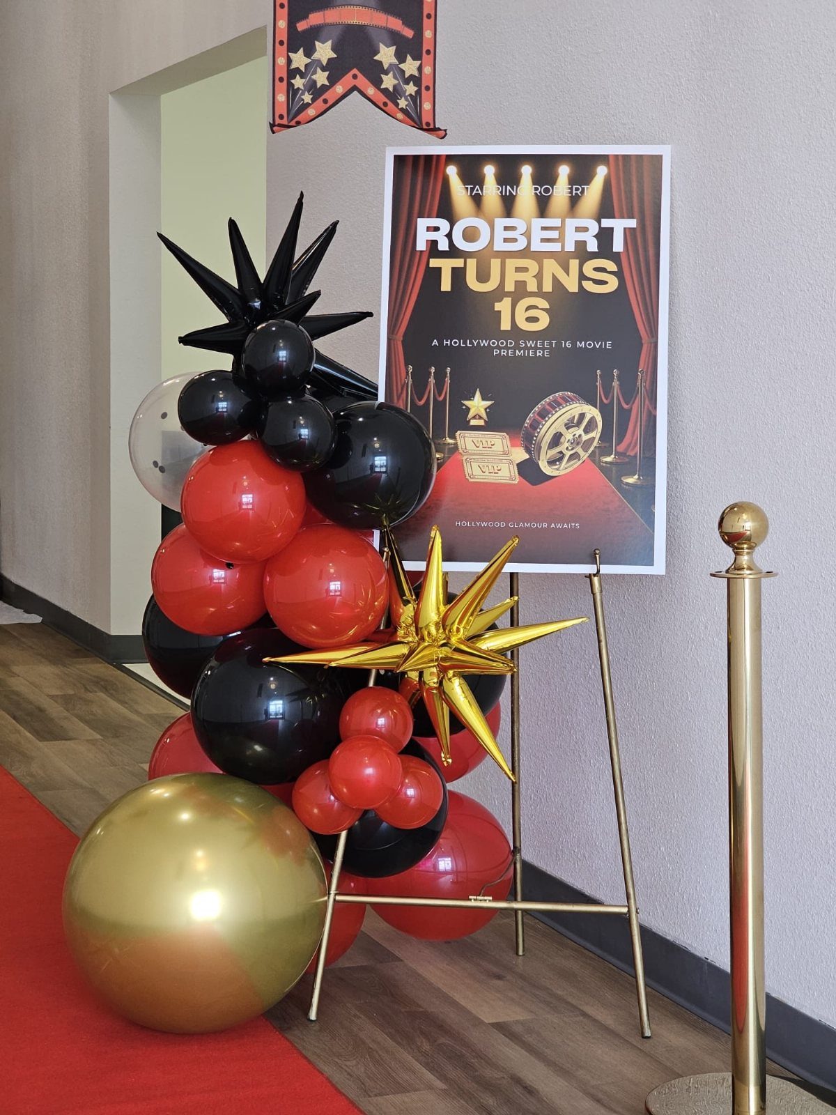 Movie premiere themed 16th birthday setup with red carpet and balloon arch.
