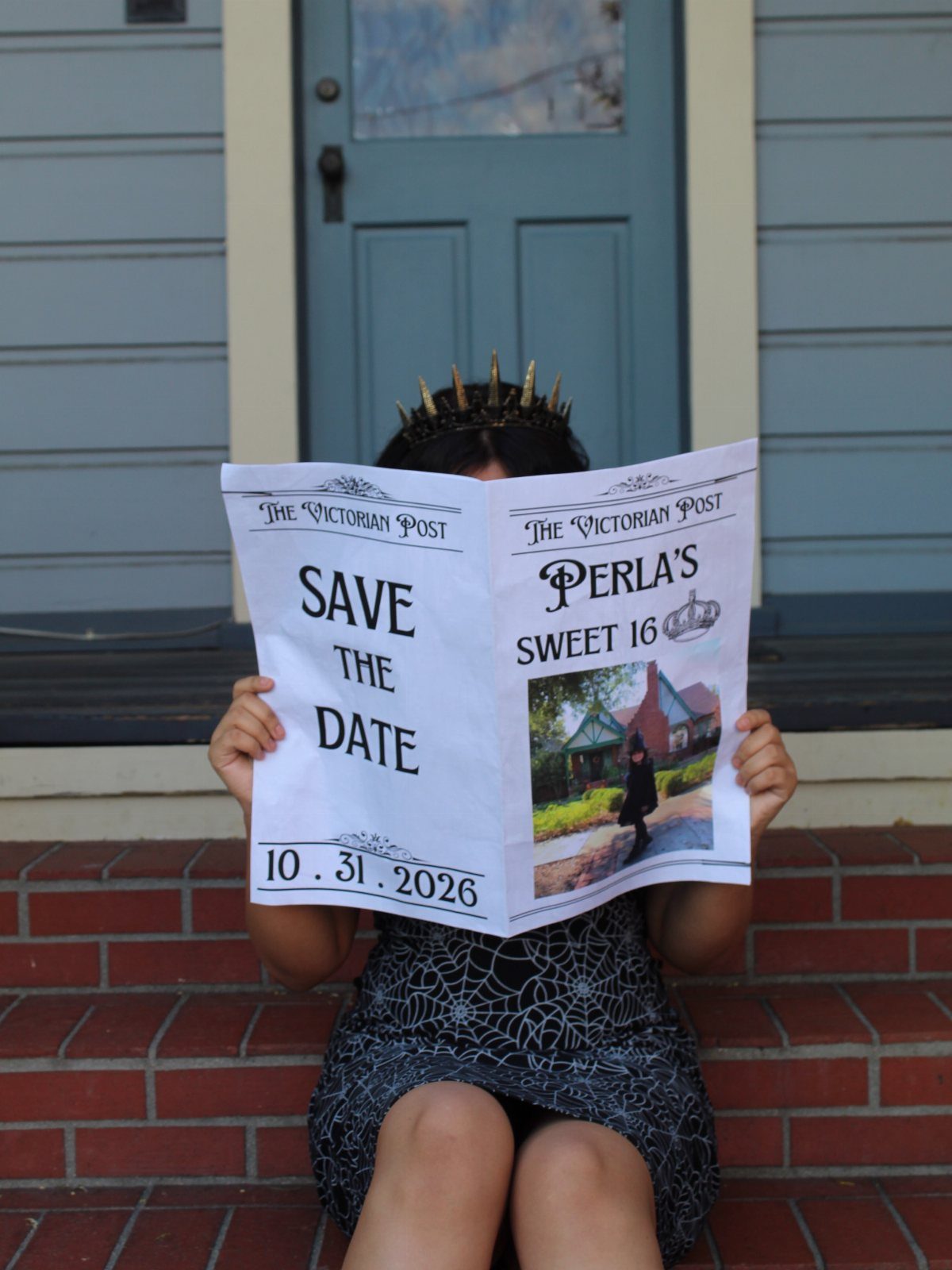 Person in spiderweb dress holding a Halloween themed Sweet 16 save the date.