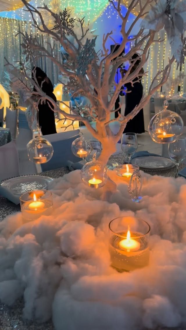 White winter tree centerpiece with glowing candles and fluffy faux snow decorations.