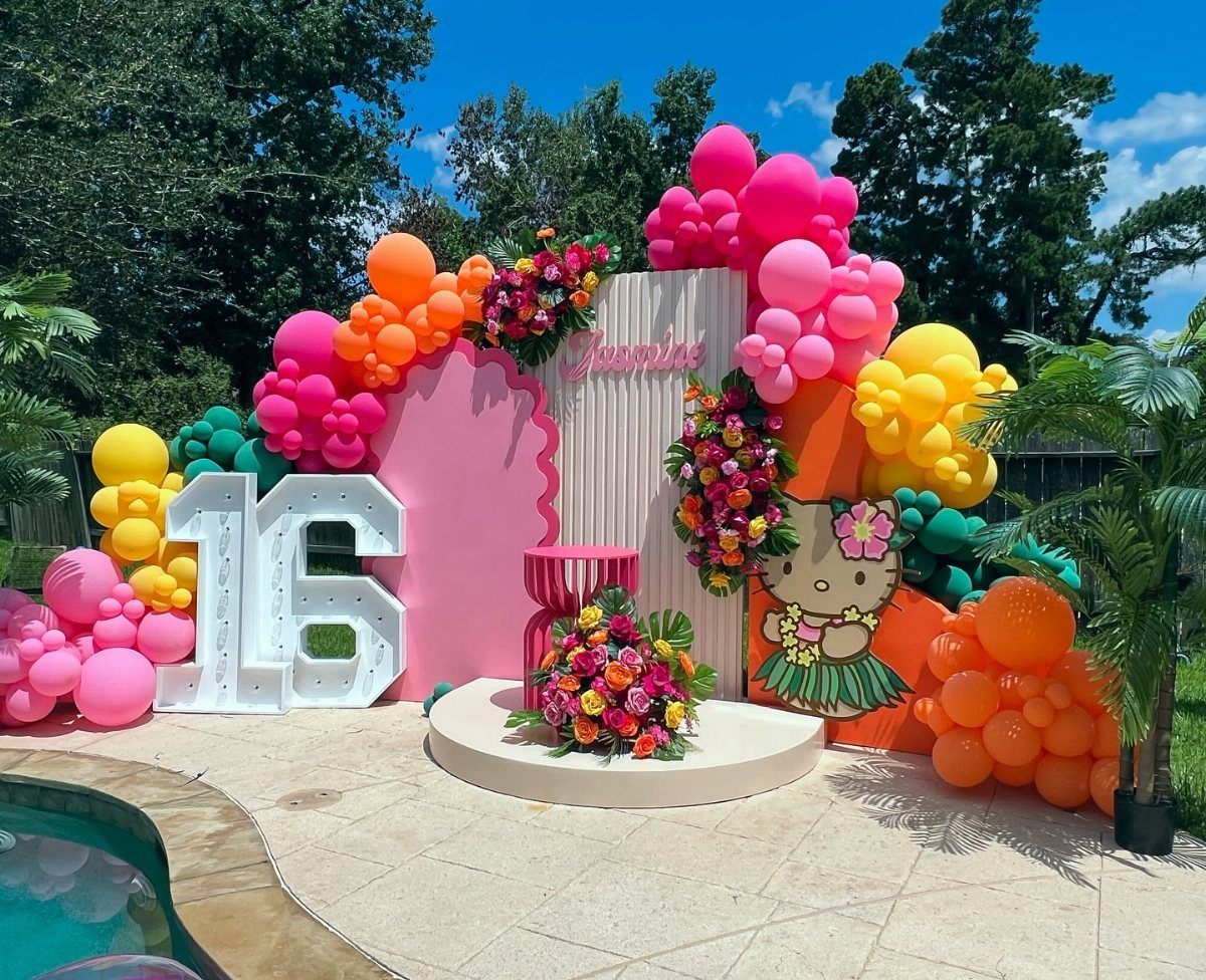 Colorful sweet sixteen party decorations with large 16 numbers, balloons, and tropical flowers.