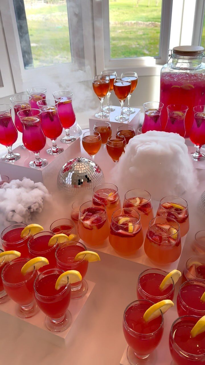 Colorful red and orange mocktails with lemon slices on white party trays.