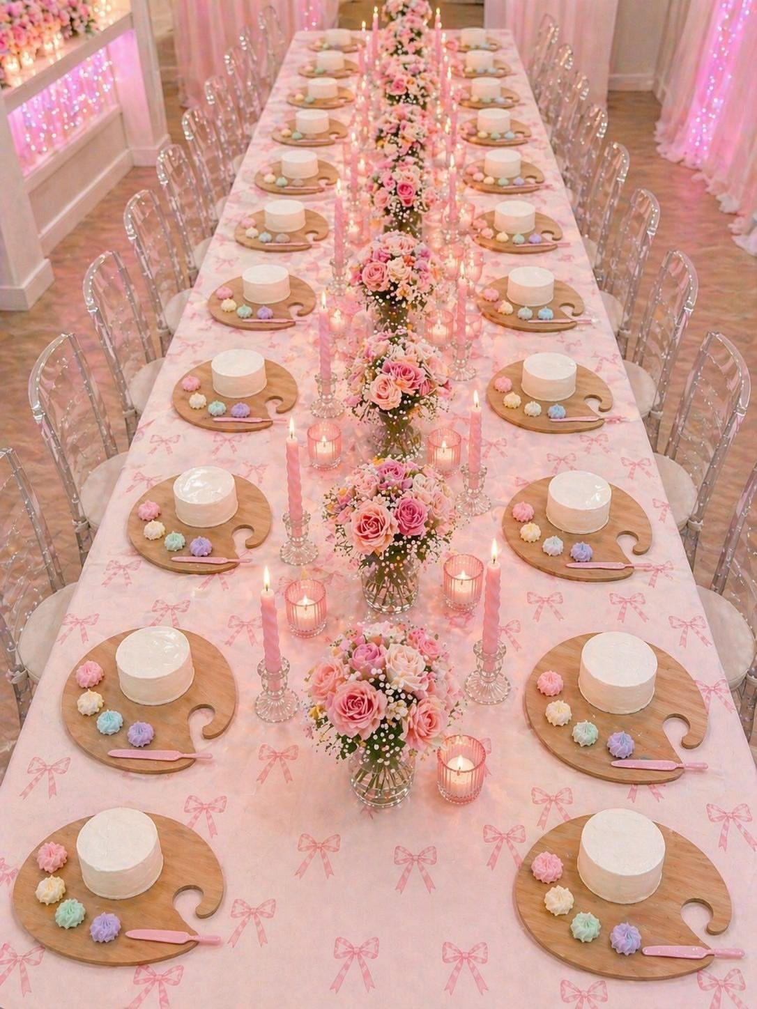 Long party table with pink tablecloth, artist palette dessert plates, and floral centerpieces.