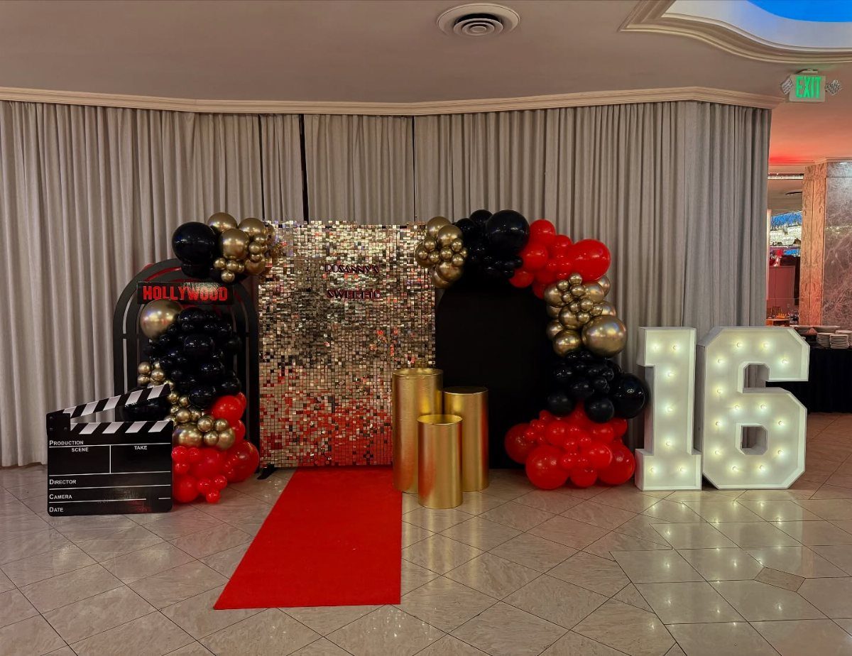 Red carpet photo booth with gold sequin backdrop, balloons, and lit 16 numbers.