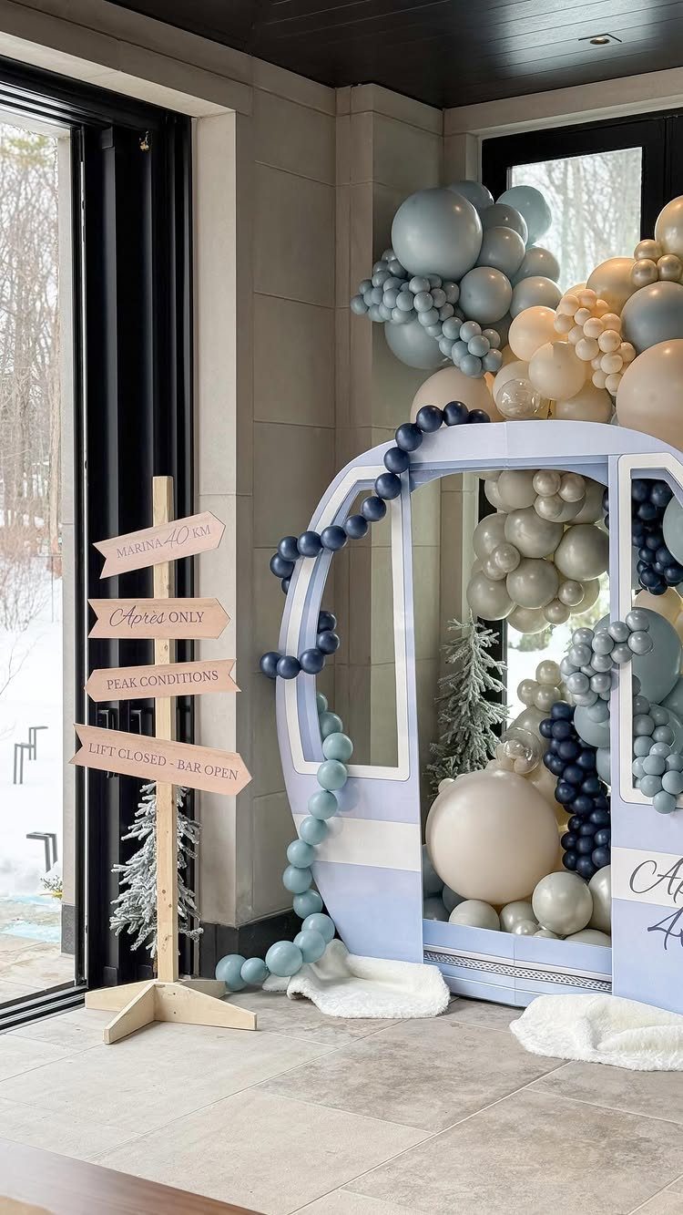 Winter themed party decor with a blue gondola filled with balloons and signpost.