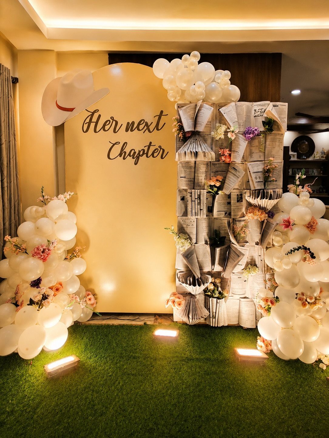 Party backdrop with gold panel, white cowboy hat, balloons, and book wall.