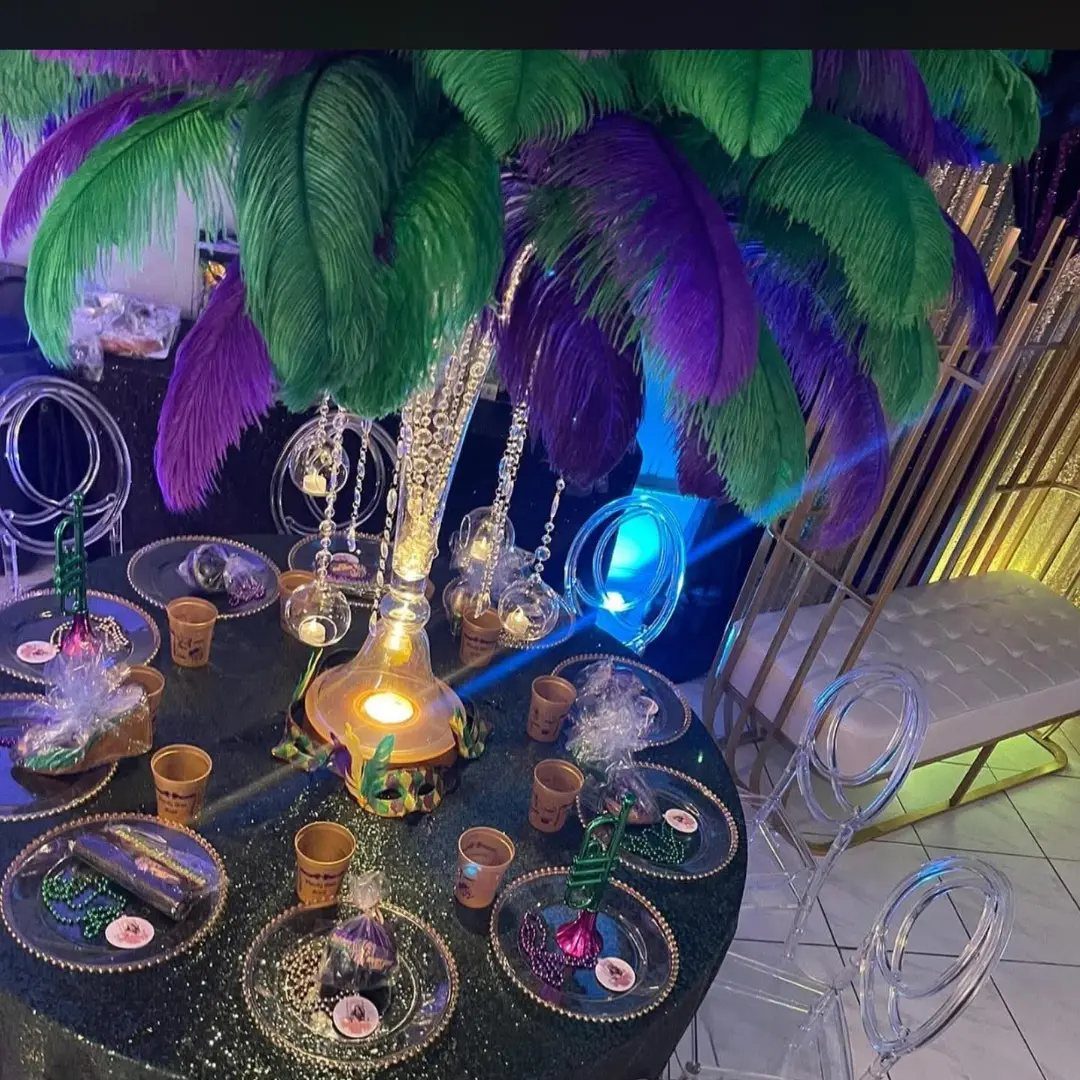 Mardi Gras party table with purple and green feathers, gold accents, and beads.