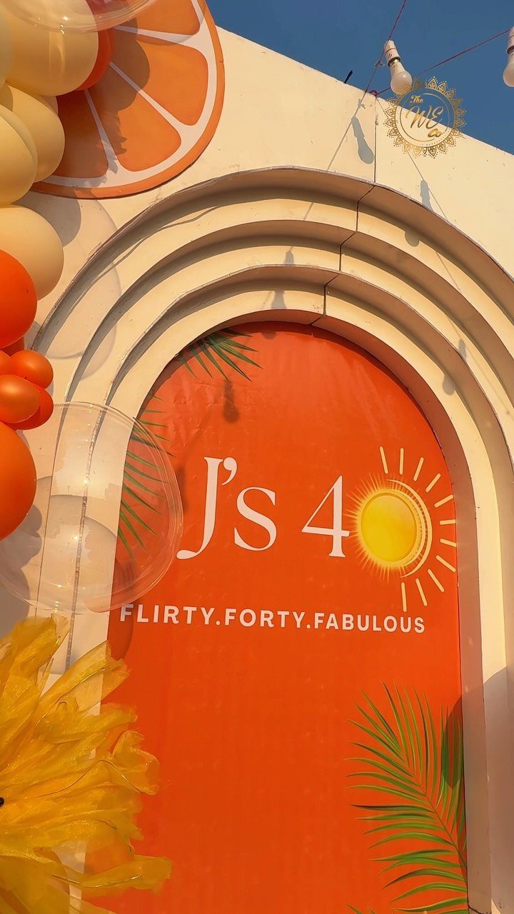 Orange party backdrop with balloons and a sign celebrating a 40th birthday.