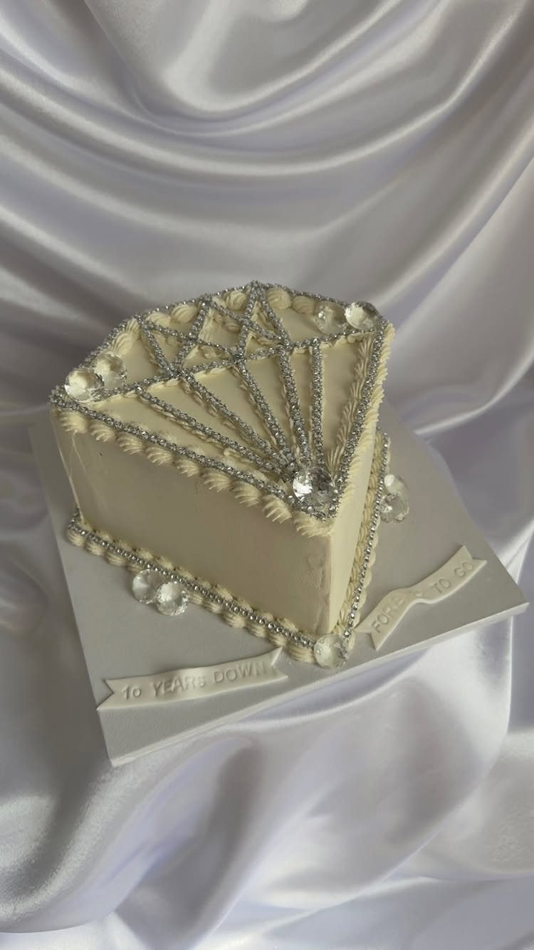 White frosted cake decorated with silver rhinestone strips in a diamond pattern